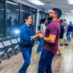 Couples enjoying salsa dance lessons at Salsa Dallas studio, practicing dance moves with a partner in a lively, friendly atmosphere.