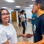 People enjoying salsa dance lessons at Salsa Dallas studio, practicing partner salsa moves in a lively, welcoming environment. Call or text 214-923-9404 to join our salsa classes today.