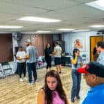 Diverse group of people enjoying salsa dance lessons at Salsa Dallas studio, with some practicing partner moves and others socializing in a friendly, energetic atmosphere. Perfect for salsa dance enthusiasts.