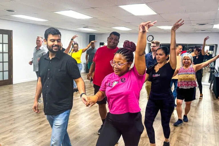 Elegant group of diverse adults practicing salsa dance steps in a lively studio class, emphasizing fun and rhythm in Dallas, Texas.