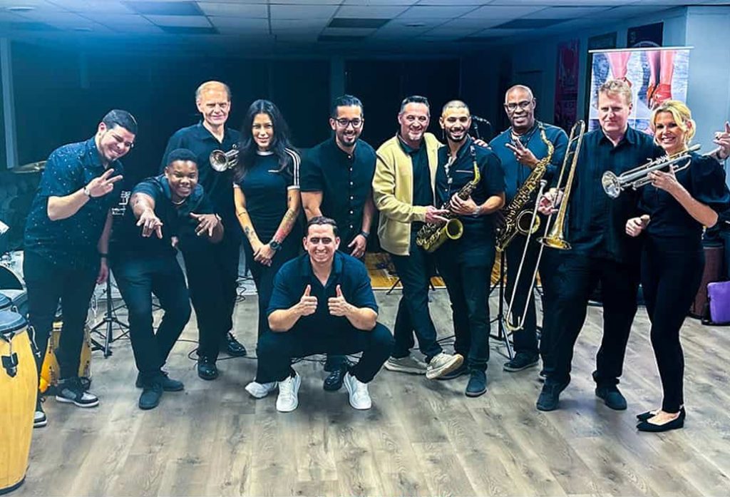 Salsa Dallas Latin dance instructors and musicians posing with instruments during salsa lessons at Salsa Dallas studio. Call or text 214-923-9404 for salsa classes and dance lessons in Dallas.
